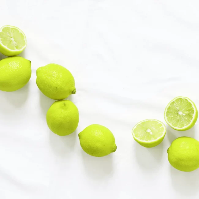 Grüne Zitronen auf einem ebenmäßigen, hellen Hintergrund